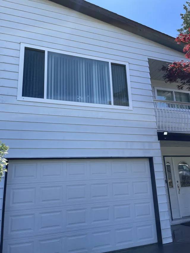 White siding around the same window and garage after cleaning.